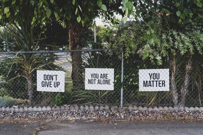 a fence displays encouraging messages on signs